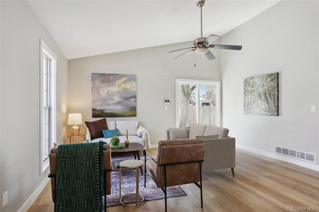 living room with ceiling fan, baseboards, light wood finished floors, and high vaulted ceiling