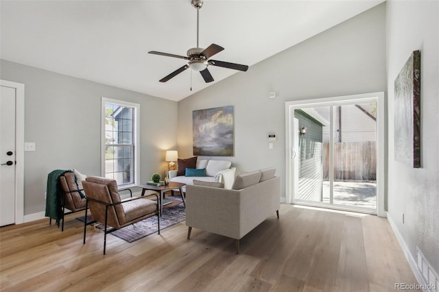 living area featuring vaulted ceiling, light wood finished floors, a ceiling fan, and baseboards