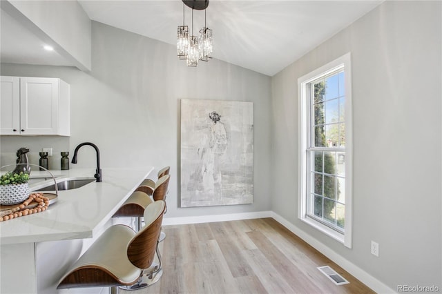 dining space featuring baseboards, light wood-style floors, vaulted ceiling, and a chandelier
