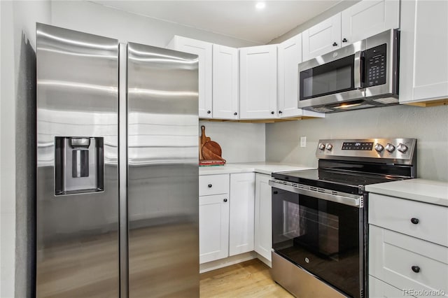 kitchen with stainless steel appliances, light countertops, white cabinets, and light wood finished floors