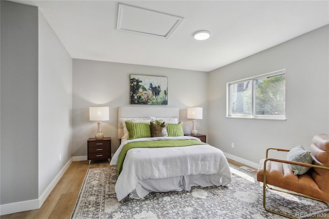bedroom with baseboards, visible vents, light wood-style flooring, and attic access