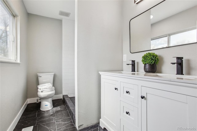 full bathroom featuring marble finish floors, toilet, baseboards, double vanity, and a shower
