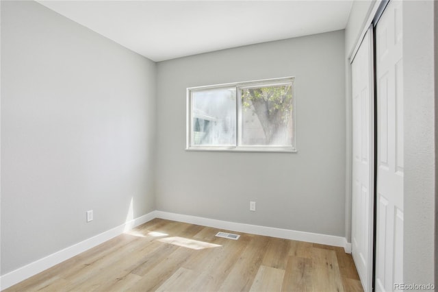 unfurnished bedroom featuring a closet, baseboards, visible vents, and light wood-style floors