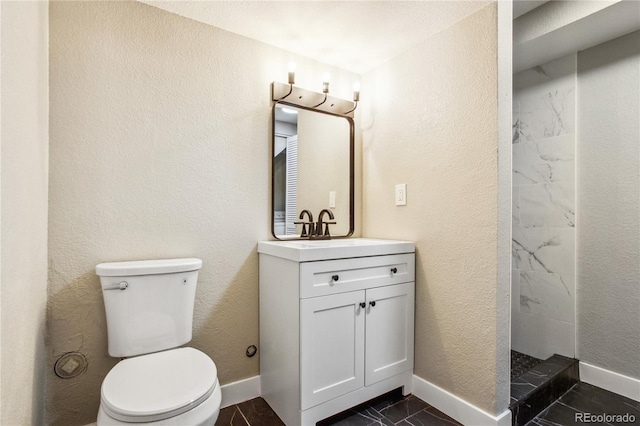 bathroom featuring baseboards, toilet, vanity, and a tile shower