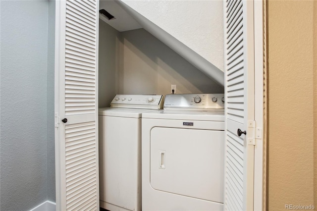 laundry room featuring laundry area, a textured wall, and washer and clothes dryer