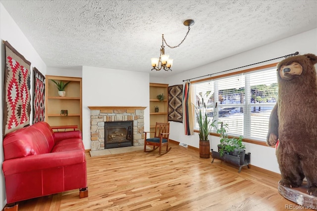 living room with a stone fireplace, hardwood / wood-style floors, a chandelier, and a textured ceiling