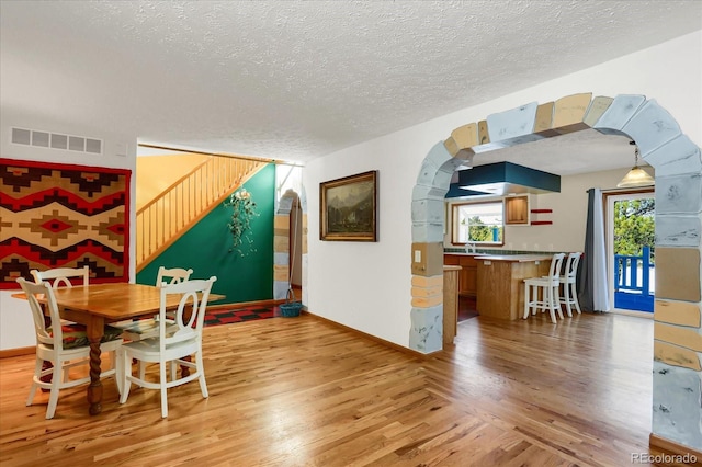 dining area featuring sink, light wood-type flooring, and a textured ceiling