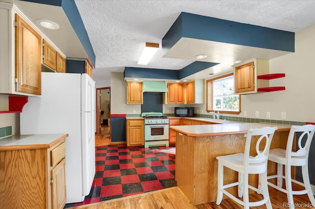 kitchen featuring kitchen peninsula, a kitchen breakfast bar, white appliances, exhaust hood, and wood-type flooring