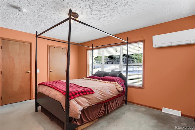 bedroom featuring a wall mounted AC, carpet, and a textured ceiling