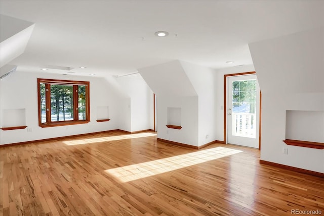 additional living space with a healthy amount of sunlight, lofted ceiling, and light hardwood / wood-style floors