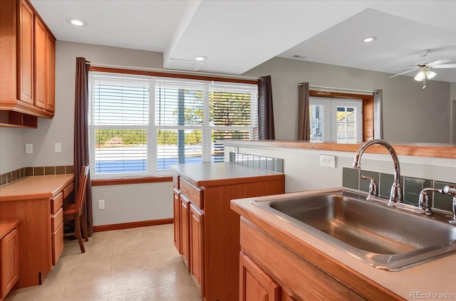 kitchen featuring light tile patterned floors, a kitchen island, ceiling fan, and sink