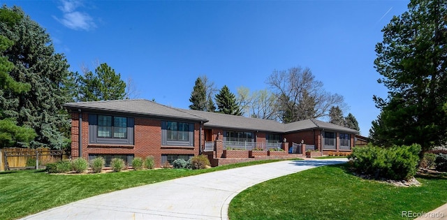view of front of home featuring brick siding, fence, and a front yard