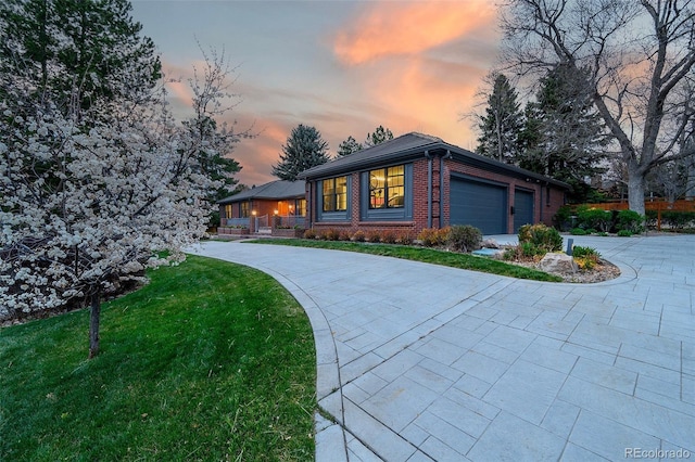 view of front facade with a lawn, a garage, driveway, and brick siding