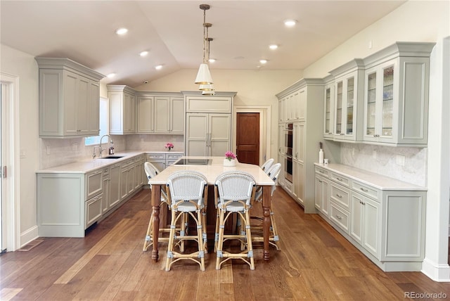 kitchen with a sink, a kitchen breakfast bar, gray cabinetry, and light countertops
