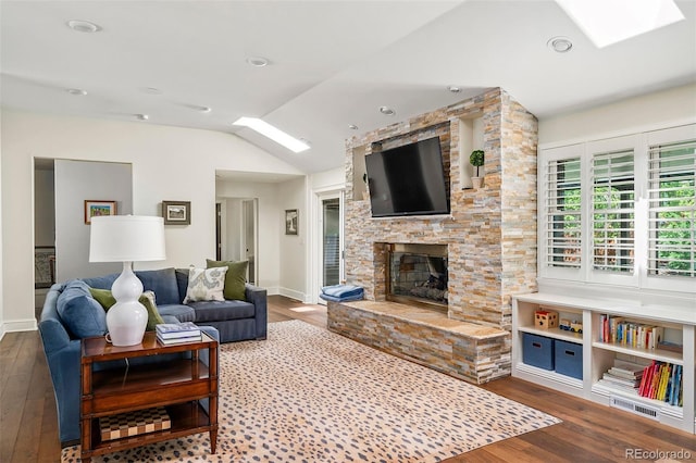 living room with baseboards, a stone fireplace, lofted ceiling with skylight, and wood finished floors