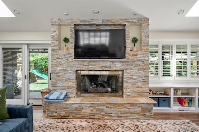 living area featuring visible vents, wood finished floors, a skylight, and a fireplace