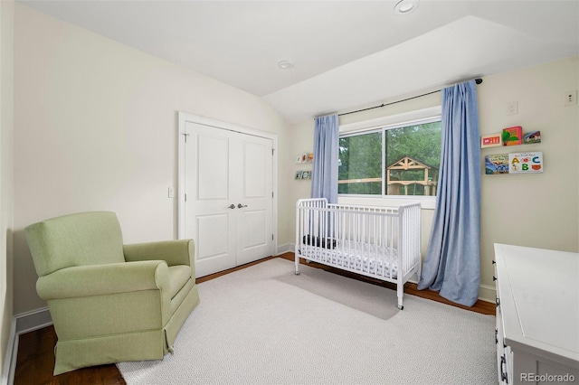 bedroom featuring a crib, recessed lighting, baseboards, wood finished floors, and lofted ceiling