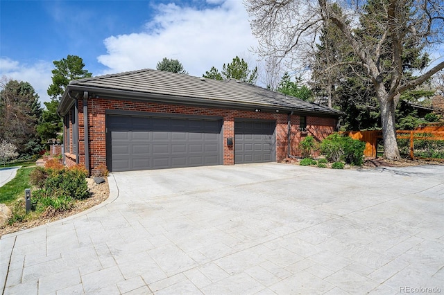 view of front of property featuring driveway, a tile roof, brick siding, fence, and an attached garage
