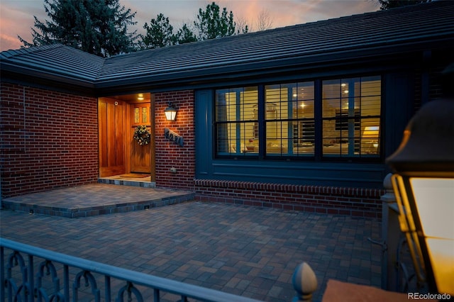 entrance to property featuring a tiled roof and brick siding