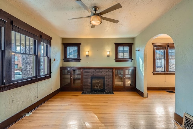 living room with ceiling fan, plenty of natural light, a textured ceiling, and light hardwood / wood-style flooring