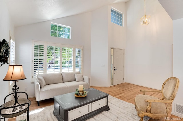 living room featuring a chandelier, wood-type flooring, and high vaulted ceiling