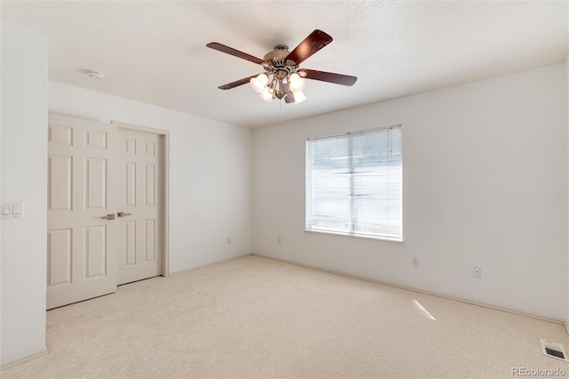 empty room with ceiling fan and light carpet