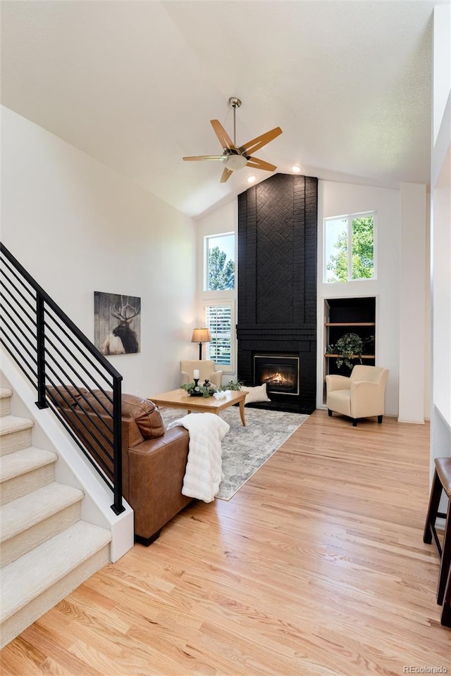 living room featuring ceiling fan, a fireplace, vaulted ceiling, and light hardwood / wood-style flooring