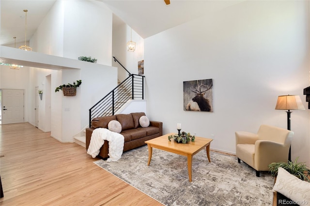 living room with a chandelier, light wood-type flooring, and high vaulted ceiling