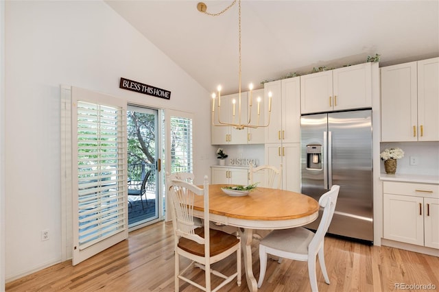 dining space with a notable chandelier, light wood-type flooring, and high vaulted ceiling