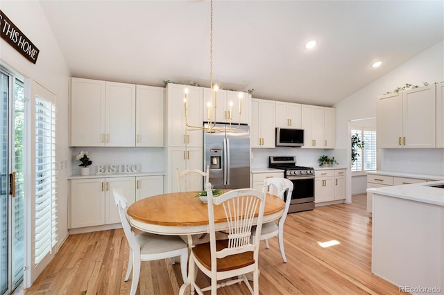 kitchen featuring white cabinets, a wealth of natural light, appliances with stainless steel finishes, and vaulted ceiling