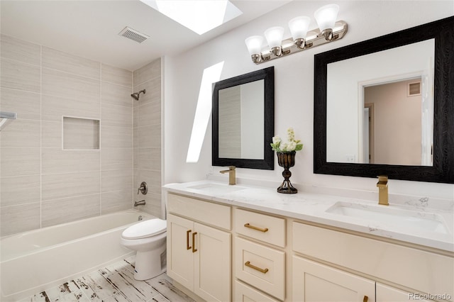 full bathroom featuring vanity, a skylight, toilet, and tiled shower / bath