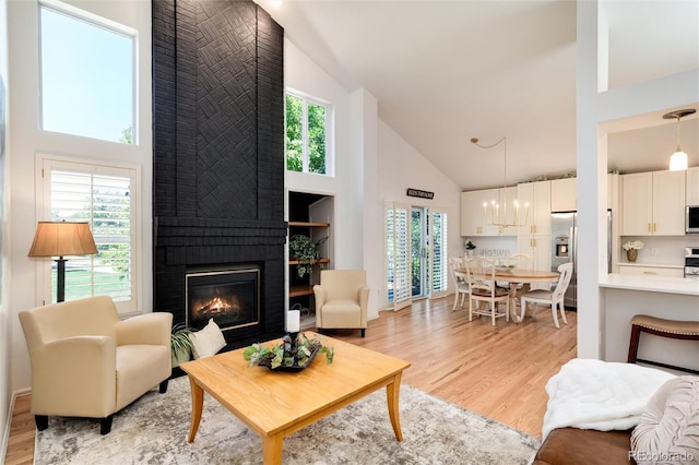 living room featuring light hardwood / wood-style floors, a fireplace, and high vaulted ceiling