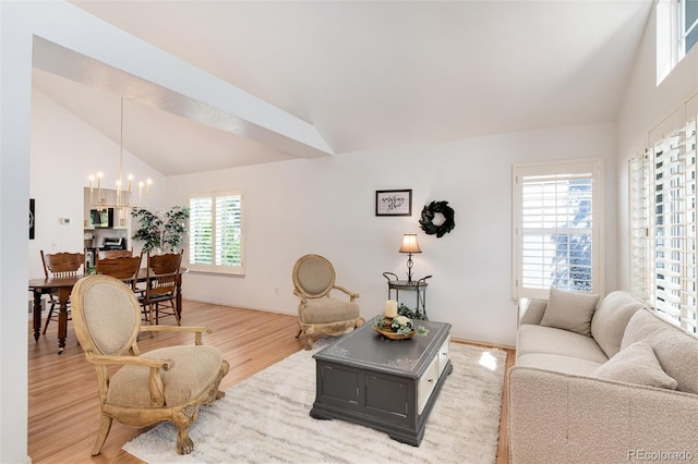 living room with high vaulted ceiling, a notable chandelier, light wood-type flooring, and a wealth of natural light