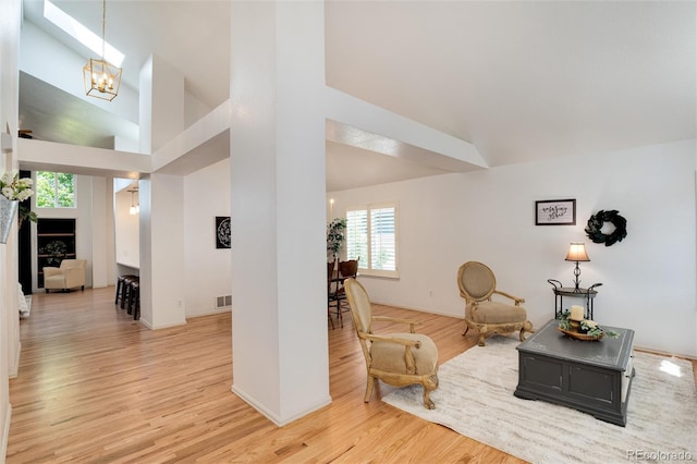 sitting room featuring light wood-type flooring, high vaulted ceiling, and a notable chandelier