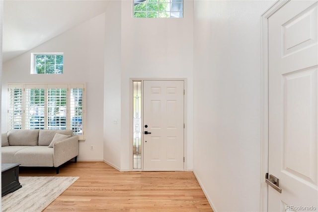 entryway with light wood-type flooring and high vaulted ceiling