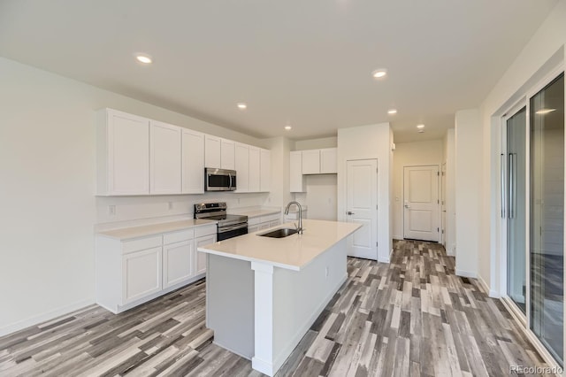 kitchen featuring sink, light wood-type flooring, an island with sink, white cabinetry, and stainless steel appliances