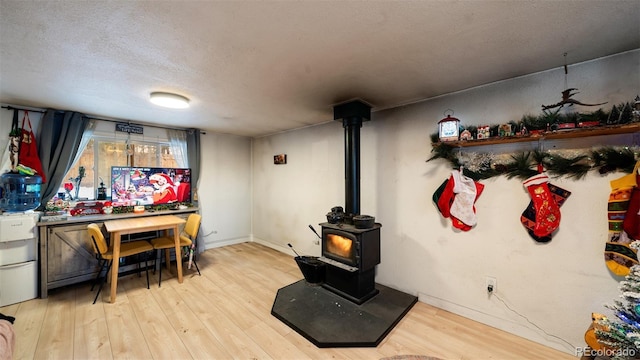 interior space featuring a textured ceiling, light hardwood / wood-style flooring, and a wood stove