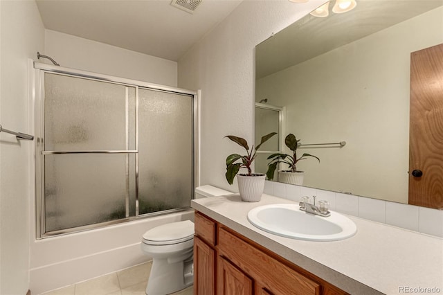 full bathroom with combined bath / shower with glass door, tile patterned floors, vanity, and toilet