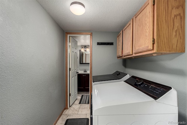 laundry room featuring cabinets, sink, independent washer and dryer, a textured ceiling, and light tile patterned floors