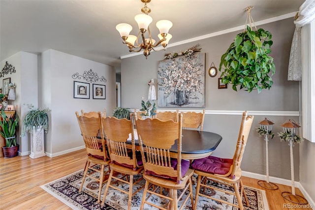 dining space with crown molding, an inviting chandelier, and hardwood / wood-style flooring