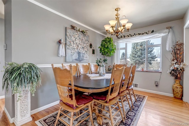 dining area featuring wood-type flooring, crown molding, and a notable chandelier