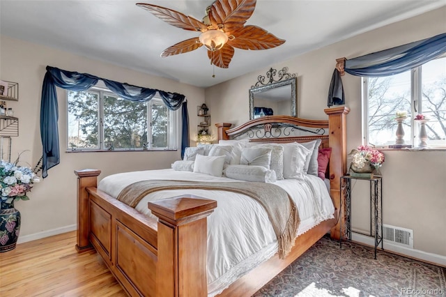 bedroom with multiple windows, ceiling fan, and light hardwood / wood-style floors