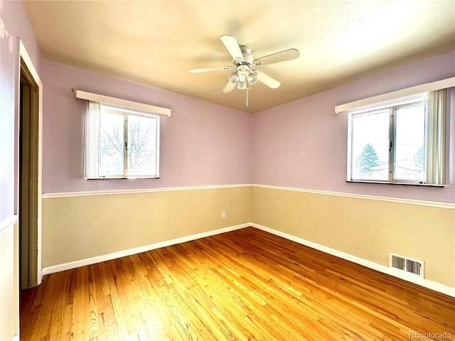 spare room featuring wood-type flooring, ceiling fan, and a healthy amount of sunlight