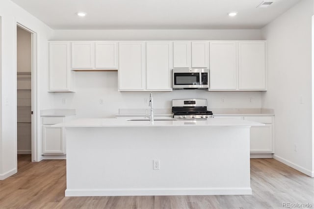 8339 Snake River St, Littleton, CO 80125 - kitchen featuring appliances with stainless steel finishes, white cabinetry, light wood finished floors, and recessed lighting