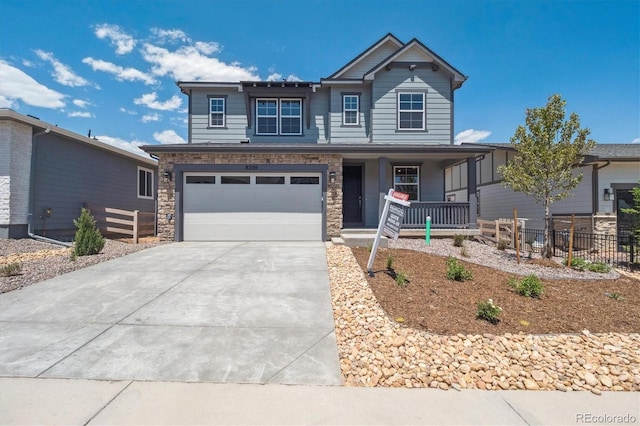 8339 Snake River St, Littleton, CO 80125 - view of front of property featuring covered porch, concrete driveway, an attached garage, and stone siding