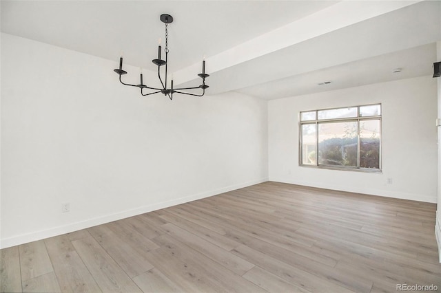 empty room with light hardwood / wood-style flooring and an inviting chandelier