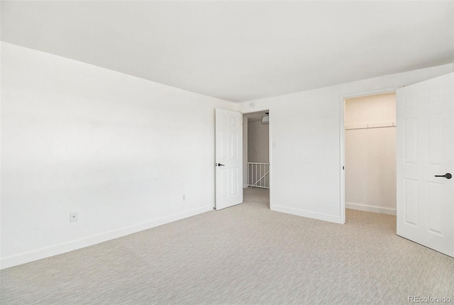 unfurnished bedroom featuring light colored carpet, a walk in closet, and a closet