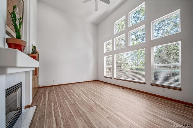 5416 S Hannibal Ct, Centennial, CO 80015 - unfurnished living room with plenty of natural light, a glass covered fireplace, ceiling fan, high vaulted ceiling, and light wood finished floors
