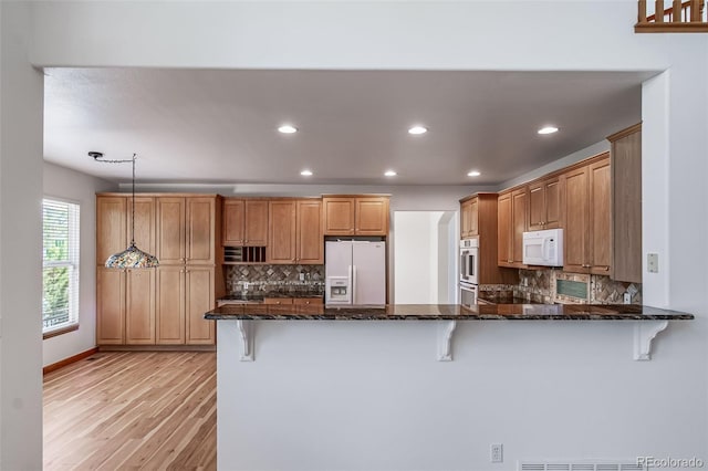 5416 S Hannibal Ct, Centennial, CO 80015 - kitchen featuring white appliances, a peninsula, a kitchen bar, light wood-style flooring, and recessed lighting