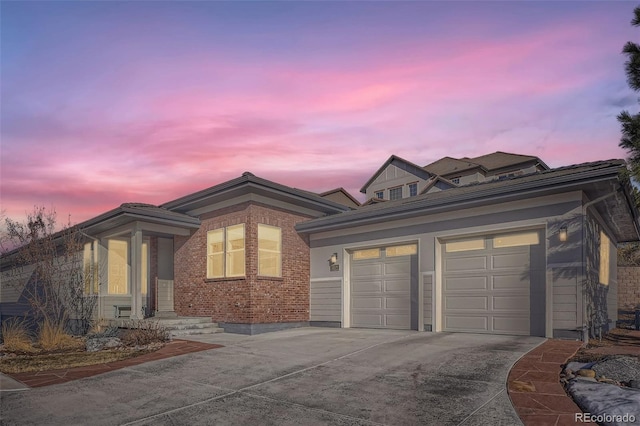 view of front of home featuring driveway, a garage, and brick siding